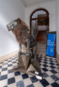 Escultura monumental de un león metálico en el hall del Palacete Gomes Freire, exhibición Pop-Up Project Lisboa.